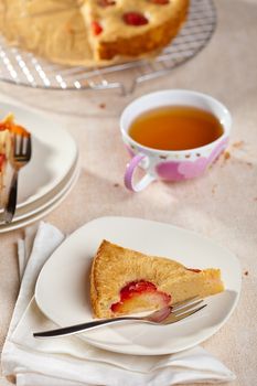 Delcious plum cake on a plate with cup of tea in background