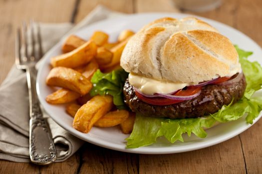 Big hamburger with onions, tomatoes and french fries