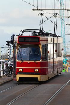 City street scene with moving red tram, bikes and crane in background