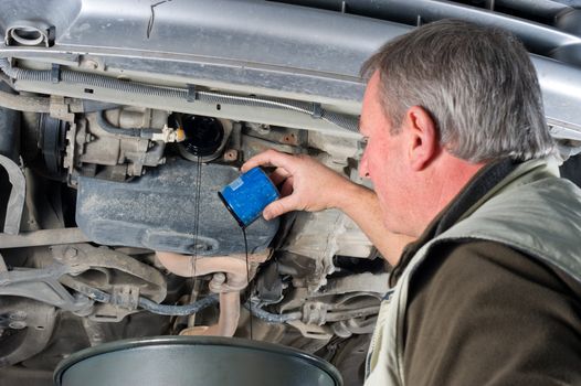 Experienced car mechanic changing oil filter on an engine