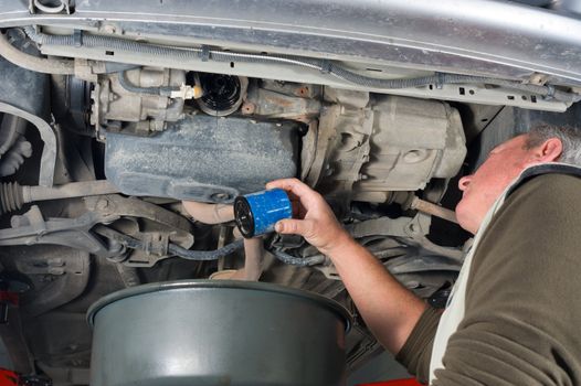 Experienced car mechanic changing oil filter on an engine