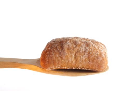 Bun on a wooden spoon against a white background