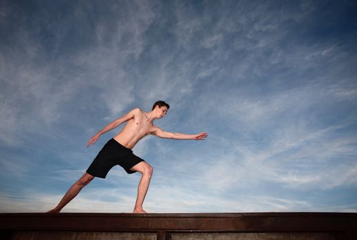 Fit young Caucasian man exercising near a steel rail outside