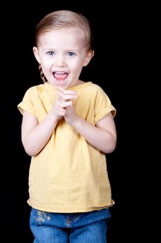 A girl with her hands clasped and her face shows a lot of excitement.