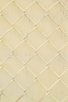 Yellow painted metal fence with yellow wooden background