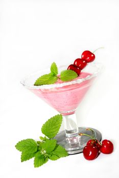 Cherry dessert in a cocktail glass with fresh lemon balm