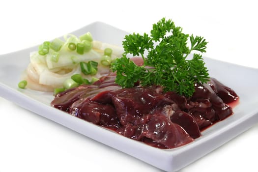 raw liver with onions and parsley on a white plate