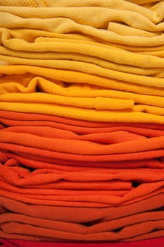 Warm colors background. Folded red, orange and yellow clothes. 
