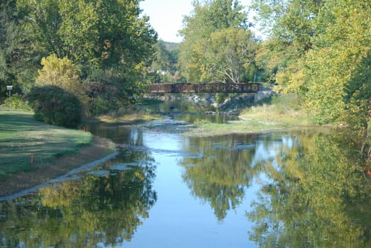 A calm stream with a bridge over it 