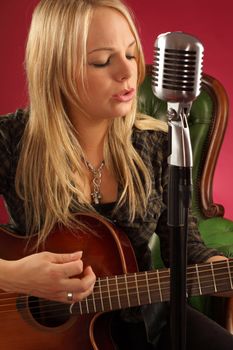 Photo of a beautiful blond female playing an acoustic guitar.