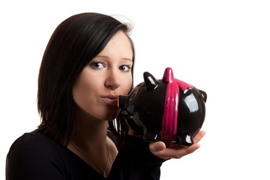 closeup of a young woman kissing a piggy bank isolated on white