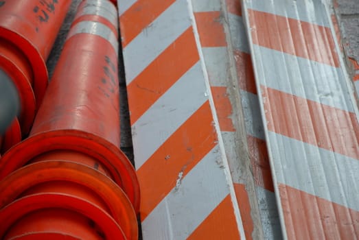 Orange safety barriers and markers piled and ready for use