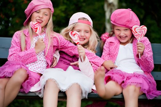 Happy children having pink clothes and a lollipop