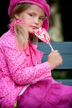 Happy children having pink clothes and a lollipop