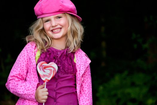 Happy children having pink clothes and a lollipop