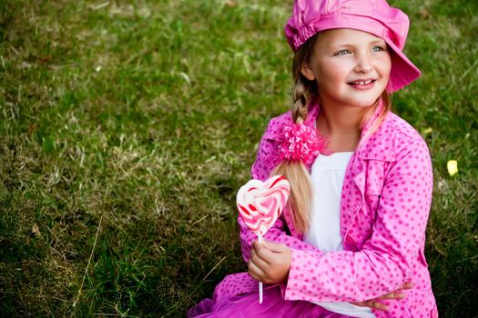 Happy children having pink clothes and a lollipop