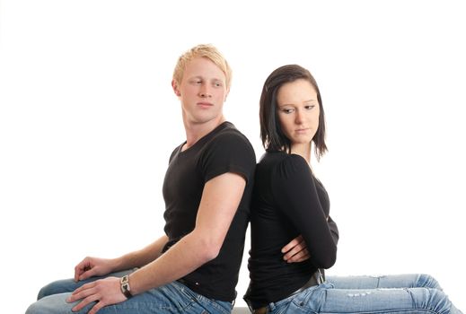 a young couple sitting back on back looking sad