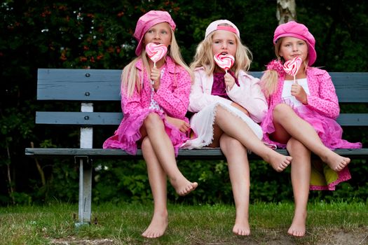 Happy children having pink clothes and a lollipop