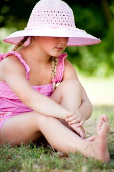 Sweet little girl in pink clothes on the grass
