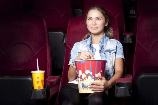 young woman sitting alone in the cinema and watching a movie