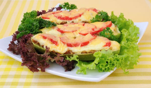 Stuffed zucchini with a mixture of vegetables with tomato and cheese with herbs