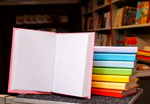 Open book with a stack of colorful books behind