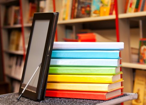 Stack of colorful books with electronic book reader