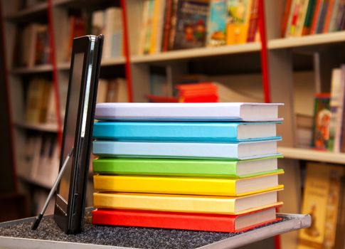 Stack of colorful books with electronic book reader