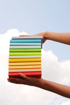 Hands holding colorful hard cover books