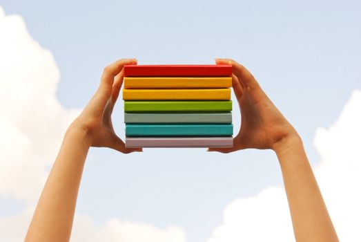 Hands holding colorful hard cover books