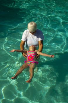 Grandmother giving granddaughter swim lessons