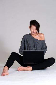 Studio shot of a multi raced yopung woman with her laptop on the floor