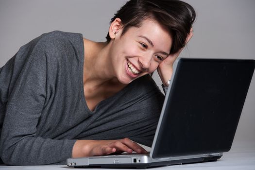 Studio shot of a multi raced yopung woman with her laptop on the floor