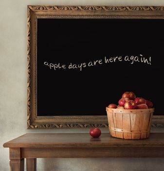 Fresh apples on wooden table with blackboard