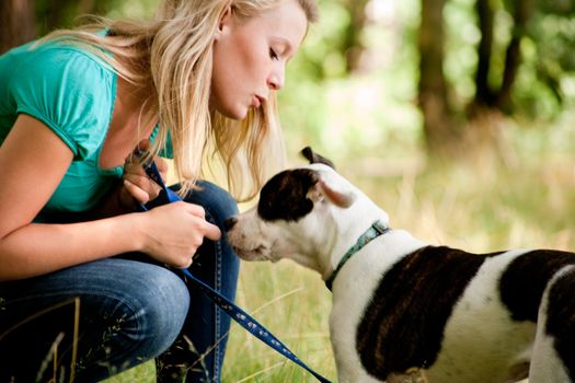 Blond girl and a american bulldog in the park