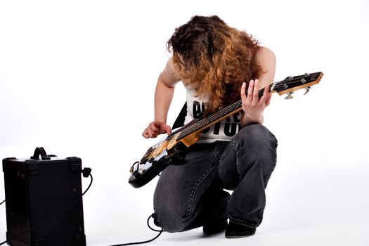 Young girl adjusting her guitar and amplifier