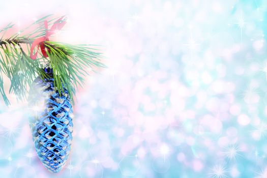 Christmas tree branch holding a pine cone ornament against a beautiful blue background with copyspace.

