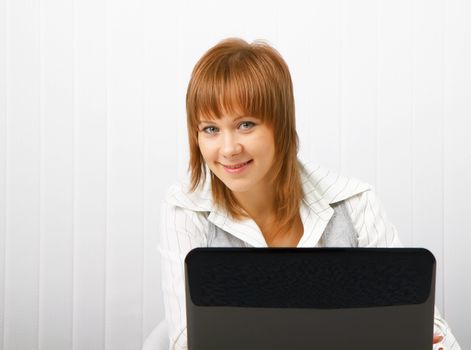 Attractive smiling happy girl with a laptop in the office
