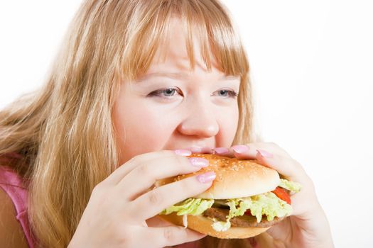 The young hungry woman bites the big hamburger