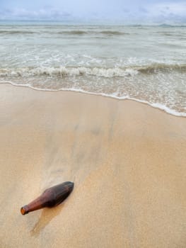 Empty glass bottle stuck inside a sandy beach in Malaysia
