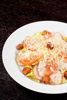 Salad of lettuce, chinese cabbage, tomato, garlic rusk, parmesan cheese, sauce and chicken meat