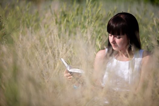 girl reading a book in the grass