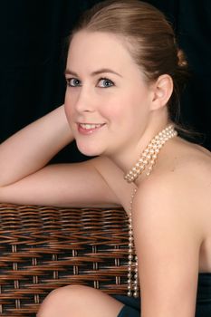 Beautiful blond female wearing pearls against a dark background