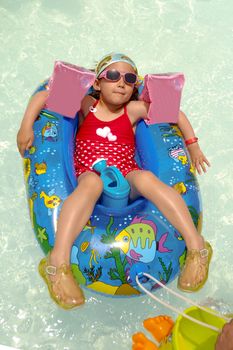 Young child is relaxing in gummiboat in swimming pool.