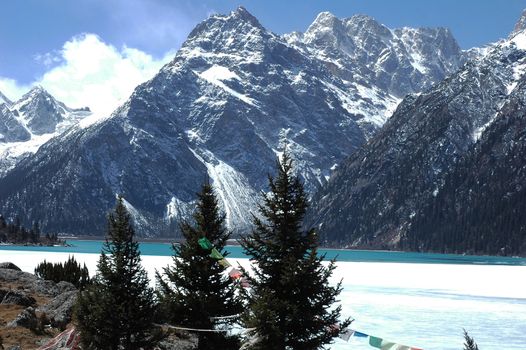 Landscape of blue lake and mountains covered with snow in winter