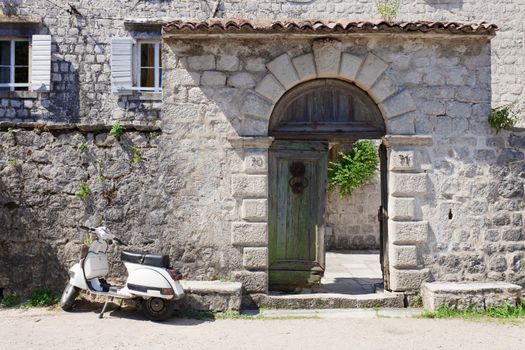 White moped next to broken old wooden gates