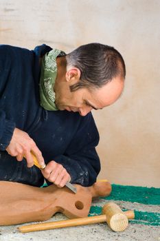 Sculptor working on a wooden statue in his studio