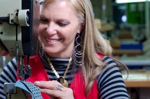 Female worker sewing leather in a footwear factory