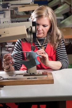 Female worker sewing leather in a footwear factory