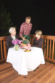 older couple in outdoor restaurant at night - waiter has served the wine to the man, to see if it is acceptable, from the look on his face it meets his requirements and is satisfactory:)